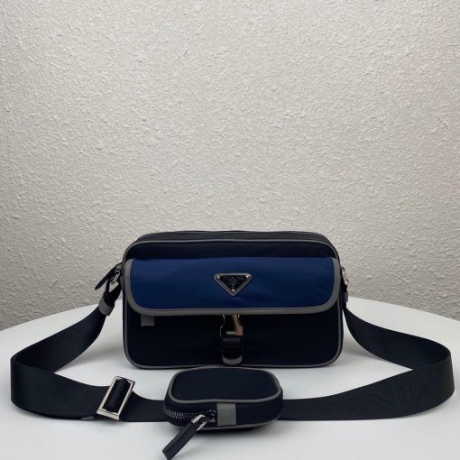 PRADA Nylon Cross-Body Bag. Original Quality Bag including gift box, care book, dust bag, authenticity card. This bag decorated with Saffiano leather trim presents compact volumes and a sleek design. With its distinctive side release buckle on the front, it comes with an easily adjustable shoulder strap. This cross-body bag featuring Saffiano leather trim with metal hardware and Prada logo lining, logo tag inside, enameled metal triangle logo outside. It has a main compartment with zipper, secondary compartment with flap and side release buckle, two front pockets, including one with zipper.