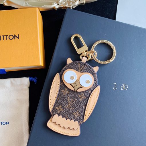 LOUIS VUITTON Owl Bag-Charm & Key Holder. Authentic quality luxury accessory crafted in genuine leather comes with authenticity card, dust bag and gift bag. Embrace whimsical elegance. The Owl bag charm and key holder showcases a lively mascot, adorned with LV stud eyes and a Monogram Flower beak. This charming accessory combines gold-color hardware, expertly blending calf leather and Monogram Eclipse canvas - both iconic materials of the House. The refined hook and ring are exquisitely engraved with the LOUIS VUITTON signature, adding an elegant touch to its overall design.