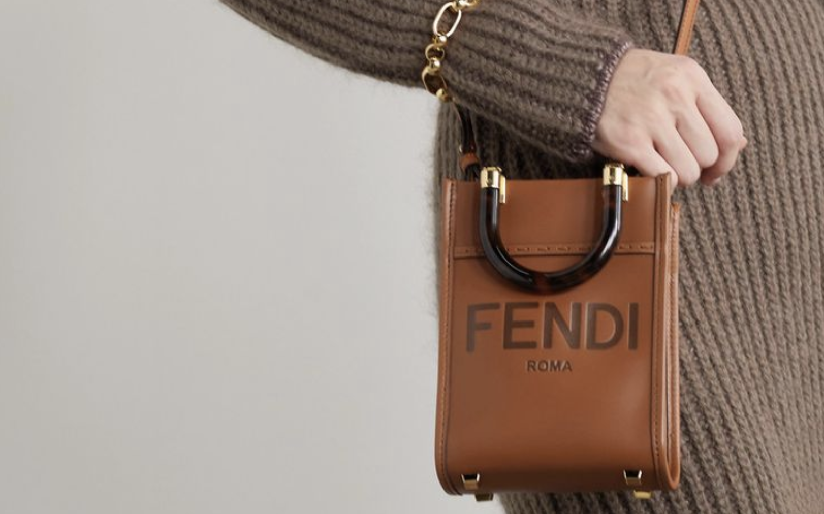 A confident woman carries a FENDI MINI SUNSHINE SHOPPER replica on a charming cobblestone street.