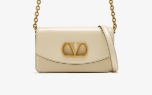 Close-up of gold V logo on VALENTINO replica clutch in studio lighting