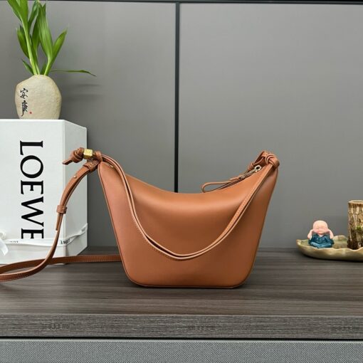LOEWE Mini Hammock Hobo. Authentic quality luxury bag crafted in genuine leather comes with authenticity card, dust bag and gift bag. Effortless Form, Everyday Function. The Mini Hammock Hobo is a contemporary reimagining of Loewe’s iconic Hammock bag. This streamlined variation offers a sleek, sculptural silhouette designed as a versatile sling bag for modern living. Expertly crafted in classic calfskin, it features soft, supple leather and a compact form that adapts effortlessly to your day. The unique design allows for multiple carry options—wear it crossbody, over the shoulder, or by hand. Elegant yet functional, this mini hobo is perfect for essentials, making it an ideal choice for both daily wear and minimalist style statements.