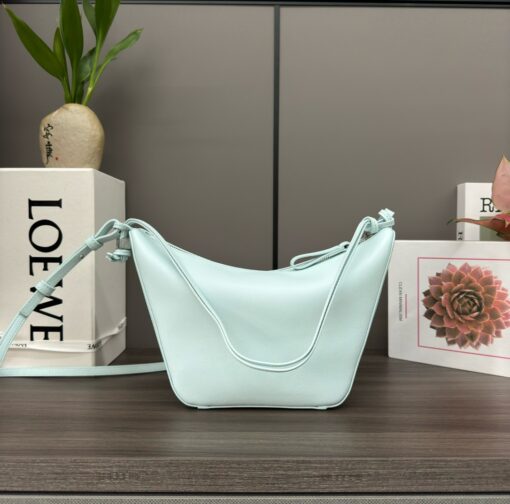LOEWE Mini Hammock Hobo. Authentic quality luxury bag crafted in genuine leather comes with authenticity card, dust bag and gift bag. Effortless Form, Everyday Function. The Mini Hammock Hobo is a contemporary reimagining of Loewe’s iconic Hammock bag. This streamlined variation offers a sleek, sculptural silhouette designed as a versatile sling bag for modern living. Expertly crafted in classic calfskin, it features soft, supple leather and a compact form that adapts effortlessly to your day. The unique design allows for multiple carry options—wear it crossbody, over the shoulder, or by hand. Elegant yet functional, this mini hobo is perfect for essentials, making it an ideal choice for both daily wear and minimalist style statements.