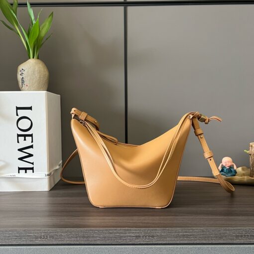 LOEWE Mini Hammock Hobo. Authentic quality luxury bag crafted in genuine leather comes with authenticity card, dust bag and gift bag. Effortless Form, Everyday Function. The Mini Hammock Hobo is a contemporary reimagining of Loewe’s iconic Hammock bag. This streamlined variation offers a sleek, sculptural silhouette designed as a versatile sling bag for modern living. Expertly crafted in classic calfskin, it features soft, supple leather and a compact form that adapts effortlessly to your day. The unique design allows for multiple carry options—wear it crossbody, over the shoulder, or by hand. Elegant yet functional, this mini hobo is perfect for essentials, making it an ideal choice for both daily wear and minimalist style statements.