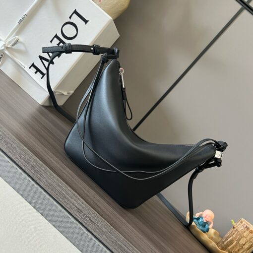 LOEWE Mini Hammock Hobo. Authentic quality luxury bag crafted in genuine leather comes with authenticity card, dust bag and gift bag. Effortless Form, Everyday Function. The Mini Hammock Hobo is a contemporary reimagining of Loewe’s iconic Hammock bag. This streamlined variation offers a sleek, sculptural silhouette designed as a versatile sling bag for modern living. Expertly crafted in classic calfskin, it features soft, supple leather and a compact form that adapts effortlessly to your day. The unique design allows for multiple carry options—wear it crossbody, over the shoulder, or by hand. Elegant yet functional, this mini hobo is perfect for essentials, making it an ideal choice for both daily wear and minimalist style statements.