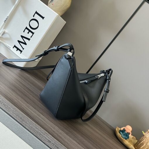 LOEWE Mini Hammock Hobo. Authentic quality luxury bag crafted in genuine leather comes with authenticity card, dust bag and gift bag. Effortless Form, Everyday Function. The Mini Hammock Hobo is a contemporary reimagining of Loewe’s iconic Hammock bag. This streamlined variation offers a sleek, sculptural silhouette designed as a versatile sling bag for modern living. Expertly crafted in classic calfskin, it features soft, supple leather and a compact form that adapts effortlessly to your day. The unique design allows for multiple carry options—wear it crossbody, over the shoulder, or by hand. Elegant yet functional, this mini hobo is perfect for essentials, making it an ideal choice for both daily wear and minimalist style statements.