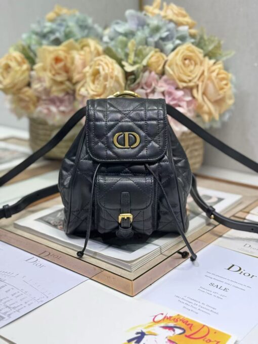 DIOR Small Caro Backpack. Authentic quality luxury bag crafted in genuine leather comes with authenticity card, dust bag and gift bag. Elegance Meets Effortless Edge. Elevate your everyday with the DIOR Small Caro Backpack — a flawless blend of modern femininity and iconic House craftsmanship. Luxuriously crafted in lambskin, its supple silhouette is enhanced by bold Macrocannage topstitching that whispers timeless Dior style. The antique gold-finish ‘CD’ clasp opens to a drawstring main compartment, perfectly balancing beauty and practicality. A discreet flap pocket keeps your daily essentials close at hand, while the top handle and adjustable leather straps offer versatile, all-day comfort. Whether slung over your shoulder or carried by hand, this petite powerhouse delivers Parisian polish in every step.