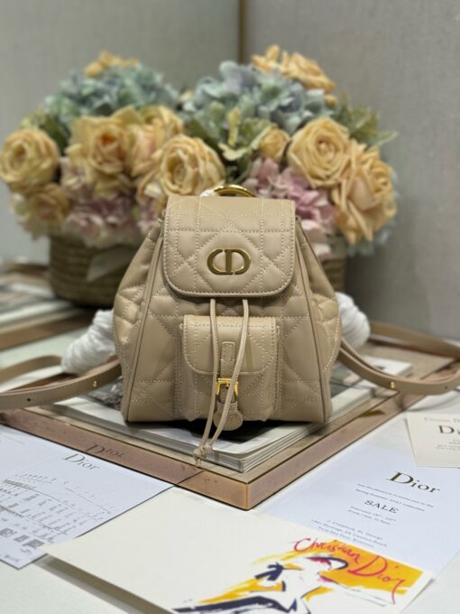 DIOR Small Caro Backpack. Authentic quality luxury bag crafted in genuine leather comes with authenticity card, dust bag and gift bag. Elegance Meets Effortless Edge. Elevate your everyday with the DIOR Small Caro Backpack — a flawless blend of modern femininity and iconic House craftsmanship. Luxuriously crafted in lambskin, its supple silhouette is enhanced by bold Macrocannage topstitching that whispers timeless Dior style. The antique gold-finish ‘CD’ clasp opens to a drawstring main compartment, perfectly balancing beauty and practicality. A discreet flap pocket keeps your daily essentials close at hand, while the top handle and adjustable leather straps offer versatile, all-day comfort. Whether slung over your shoulder or carried by hand, this petite powerhouse delivers Parisian polish in every step.