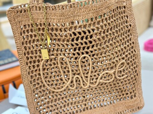 CHLOÉ Summer Banana Tote Bag. Authentic quality luxury bag crafted in genuine leather comes with authenticity card, dust bag and gift bag. Heritage in Hand: Where Artisan Craft Meets Summer Elegance. Introducing the Summer Banana Tote—an artisanal masterpiece crafted from raffia and calfskin by a single artisan over 4.5 days in partnership with Made For A Woman. This spacious tote is adorned with a handwritten signature inspired by Chloé’s rich heritage, while a playful dangling chain and delicate charms add the perfect finishing touch. A celebration of craftsmanship and effortless summer style.