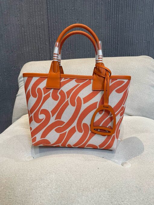 HERMÈS Steeple 25 Bag. Authentic quality luxury bag crafted in genuine leather comes with authenticity card, dust bag and gift bag. Where art meets heritage. The Hermès Steeple Bag is a charming fusion of heritage and artistry, crafted from a blend of canvas and Swift leather. Its design pays tribute to Hermès’ equestrian roots with whip-shaped handles and a stirrup-inspired charm, adding a playful yet sophisticated touch. Lightweight yet spacious, the Steeple is ideal for daily use. Whether you opt for a vibrant motif or a sleek, single-color design, this bag stands out as an artistic expression of luxury that seamlessly integrates into a modern lifestyle. Praised for its unique aesthetic and accessibility within the Hermès lineup, the Steeple Bag is adored by fashion enthusiasts who appreciate its colorful palette and bold personality. While it’s best suited for those who enjoy the texture and look of canvas, it remains a versatile statement piece that captures the spirit of everyday elegance.