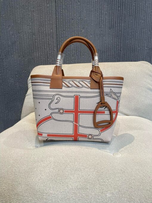 HERMÈS Steeple 25 Bag. Authentic quality luxury bag crafted in genuine leather comes with authenticity card, dust bag and gift bag. Where art meets heritage. The Hermès Steeple Bag is a charming fusion of heritage and artistry, crafted from a blend of canvas and Swift leather. Its design pays tribute to Hermès’ equestrian roots with whip-shaped handles and a stirrup-inspired charm, adding a playful yet sophisticated touch. Lightweight yet spacious, the Steeple is ideal for daily use. Whether you opt for a vibrant motif or a sleek, single-color design, this bag stands out as an artistic expression of luxury that seamlessly integrates into a modern lifestyle. Praised for its unique aesthetic and accessibility within the Hermès lineup, the Steeple Bag is adored by fashion enthusiasts who appreciate its colorful palette and bold personality. While it’s best suited for those who enjoy the texture and look of canvas, it remains a versatile statement piece that captures the spirit of everyday elegance.