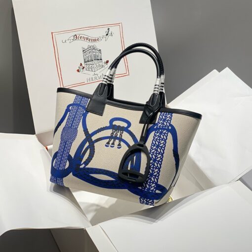 HERMÈS Steeple 25 Bag. Authentic quality luxury bag crafted in genuine leather comes with authenticity card, dust bag and gift bag. Where art meets heritage. The Hermès Steeple Bag is a charming fusion of heritage and artistry, crafted from a blend of canvas and Swift leather. Its design pays tribute to Hermès’ equestrian roots with whip-shaped handles and a stirrup-inspired charm, adding a playful yet sophisticated touch. Lightweight yet spacious, the Steeple is ideal for daily use. Whether you opt for a vibrant motif or a sleek, single-color design, this bag stands out as an artistic expression of luxury that seamlessly integrates into a modern lifestyle. Praised for its unique aesthetic and accessibility within the Hermès lineup, the Steeple Bag is adored by fashion enthusiasts who appreciate its colorful palette and bold personality. While it’s best suited for those who enjoy the texture and look of canvas, it remains a versatile statement piece that captures the spirit of everyday elegance.