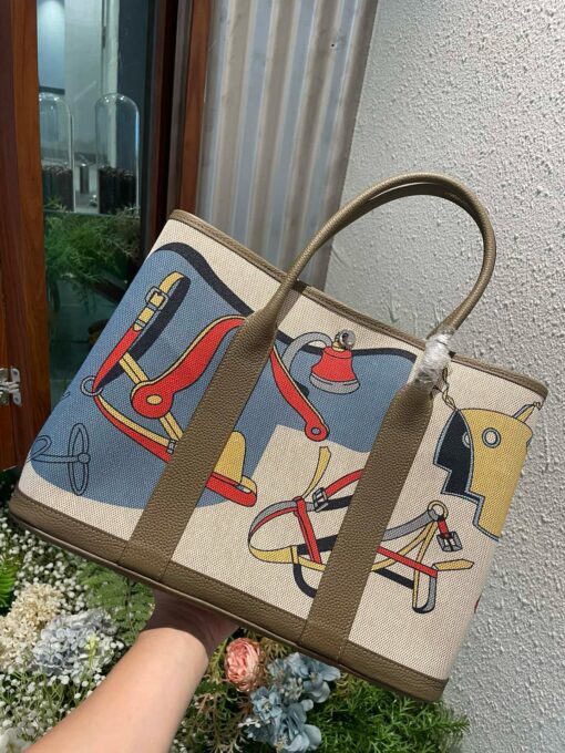 HERMÈS Garden Party Voyage. Authentic quality luxury bag crafted in genuine leather comes with authenticity card, dust bag and gift bag. The Art of Everyday Escape. Chic, structured, and effortlessly refined, the HERMÈS Garden Party Voyage is the perfect companion for your daily adventures or spontaneous weekend getaways. Crafted with precision in supple Negonda leather or canvas with leather trim, this midsize tote strikes the perfect balance between luxury and functionality. Its minimalist silhouette is elevated by discreet Clou de Selle snap closures and expandable sides, offering both form and flexibility. Spacious enough for your essentials yet compact enough to carry with ease, it’s a timeless piece designed to move with you—gracefully. Whether carried in hand or worn over the shoulder, the Garden Party Voyage 36 speaks in whispers of elegance and unmistakable HERMÈS craftsmanship. Every day is a journey. Travel beautifully.