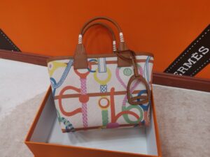 HERMÈS Steeple 25 Bag. Authentic quality luxury bag crafted in genuine leather comes with authenticity card, dust bag and gift bag. Where art meets heritage. The Hermès Steeple Bag is a charming fusion of heritage and artistry, crafted from a blend of canvas and Swift leather. Its design pays tribute to Hermès’ equestrian roots with whip-shaped handles and a stirrup-inspired charm, adding a playful yet sophisticated touch. Lightweight yet spacious, the Steeple is ideal for daily use. Whether you opt for a vibrant motif or a sleek, single-color design, this bag stands out as an artistic expression of luxury that seamlessly integrates into a modern lifestyle. Praised for its unique aesthetic and accessibility within the Hermès lineup, the Steeple Bag is adored by fashion enthusiasts who appreciate its colorful palette and bold personality. While it’s best suited for those who enjoy the texture and look of canvas, it remains a versatile statement piece that captures the spirit of everyday elegance. - KRIS + KIKO HERMÈS Steeple 25 Bag. Authentic quality luxury bag crafted in genuine leather comes with authenticity card, dust bag and gift bag. Where art meets heritage. The Hermès Steeple Bag is a charming fusion of heritage and artistry, crafted from a blend of canvas and Swift leather. Its design pays tribute to Hermès’ equestrian roots with whip-shaped handles and a stirrup-inspired charm, adding a playful yet sophisticated touch. Lightweight yet spacious, the Steeple is ideal for daily use. Whether you opt for a vibrant motif or a sleek, single-color design, this bag stands out as an artistic expression of luxury that seamlessly integrates into a modern lifestyle. Praised for its unique aesthetic and accessibility within the Hermès lineup, the Steeple Bag is adored by fashion enthusiasts who appreciate its colorful palette and bold personality. While it’s best suited for those who enjoy the texture and look of canvas, it remains a versatile statement piece that captures the spirit of everyday elegance.