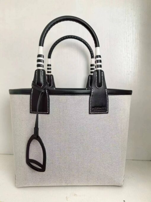 HERMÈS Steeple 25 Bag. Authentic quality luxury bag crafted in genuine leather comes with authenticity card, dust bag and gift bag. Where art meets heritage. The Hermès Steeple Bag is a charming fusion of heritage and artistry, crafted from a blend of canvas and Swift leather. Its design pays tribute to Hermès’ equestrian roots with whip-shaped handles and a stirrup-inspired charm, adding a playful yet sophisticated touch. Lightweight yet spacious, the Steeple is ideal for daily use. Whether you opt for a vibrant motif or a sleek, single-color design, this bag stands out as an artistic expression of luxury that seamlessly integrates into a modern lifestyle. Praised for its unique aesthetic and accessibility within the Hermès lineup, the Steeple Bag is adored by fashion enthusiasts who appreciate its colorful palette and bold personality. While it’s best suited for those who enjoy the texture and look of canvas, it remains a versatile statement piece that captures the spirit of everyday elegance.