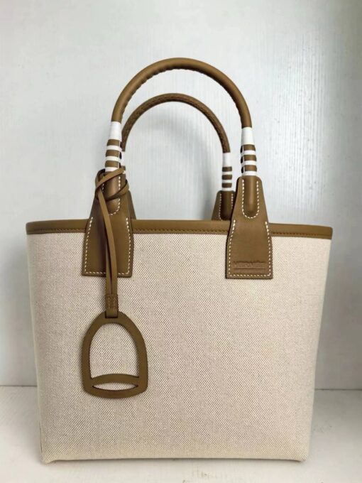 HERMÈS Steeple 25 Bag. Authentic quality luxury bag crafted in genuine leather comes with authenticity card, dust bag and gift bag. Where art meets heritage. The Hermès Steeple Bag is a charming fusion of heritage and artistry, crafted from a blend of canvas and Swift leather. Its design pays tribute to Hermès’ equestrian roots with whip-shaped handles and a stirrup-inspired charm, adding a playful yet sophisticated touch. Lightweight yet spacious, the Steeple is ideal for daily use. Whether you opt for a vibrant motif or a sleek, single-color design, this bag stands out as an artistic expression of luxury that seamlessly integrates into a modern lifestyle. Praised for its unique aesthetic and accessibility within the Hermès lineup, the Steeple Bag is adored by fashion enthusiasts who appreciate its colorful palette and bold personality. While it’s best suited for those who enjoy the texture and look of canvas, it remains a versatile statement piece that captures the spirit of everyday elegance.
