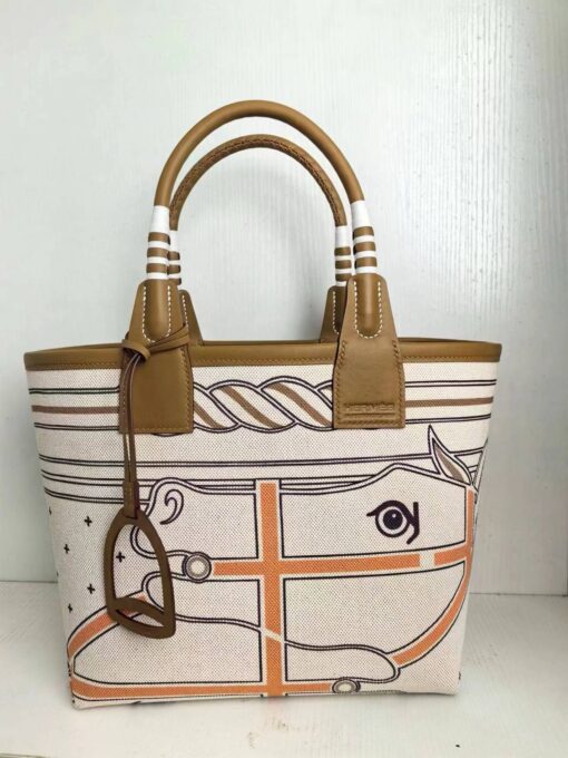 HERMÈS Steeple 25 Bag. Authentic quality luxury bag crafted in genuine leather comes with authenticity card, dust bag and gift bag. Where art meets heritage. The Hermès Steeple Bag is a charming fusion of heritage and artistry, crafted from a blend of canvas and Swift leather. Its design pays tribute to Hermès’ equestrian roots with whip-shaped handles and a stirrup-inspired charm, adding a playful yet sophisticated touch. Lightweight yet spacious, the Steeple is ideal for daily use. Whether you opt for a vibrant motif or a sleek, single-color design, this bag stands out as an artistic expression of luxury that seamlessly integrates into a modern lifestyle. Praised for its unique aesthetic and accessibility within the Hermès lineup, the Steeple Bag is adored by fashion enthusiasts who appreciate its colorful palette and bold personality. While it’s best suited for those who enjoy the texture and look of canvas, it remains a versatile statement piece that captures the spirit of everyday elegance.