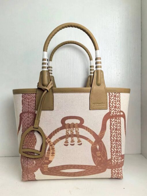 HERMÈS Steeple 25 Bag. Authentic quality luxury bag crafted in genuine leather comes with authenticity card, dust bag and gift bag. Where art meets heritage. The Hermès Steeple Bag is a charming fusion of heritage and artistry, crafted from a blend of canvas and Swift leather. Its design pays tribute to Hermès’ equestrian roots with whip-shaped handles and a stirrup-inspired charm, adding a playful yet sophisticated touch. Lightweight yet spacious, the Steeple is ideal for daily use. Whether you opt for a vibrant motif or a sleek, single-color design, this bag stands out as an artistic expression of luxury that seamlessly integrates into a modern lifestyle. Praised for its unique aesthetic and accessibility within the Hermès lineup, the Steeple Bag is adored by fashion enthusiasts who appreciate its colorful palette and bold personality. While it’s best suited for those who enjoy the texture and look of canvas, it remains a versatile statement piece that captures the spirit of everyday elegance.