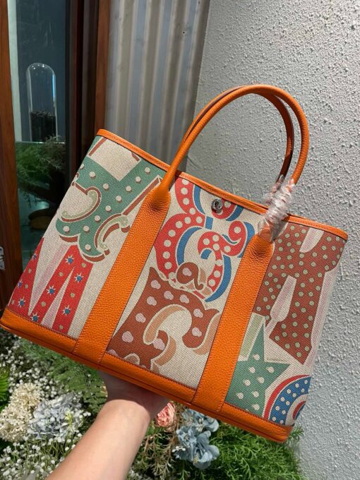 HERMÈS Garden Party Voyage. Authentic quality luxury bag crafted in genuine leather comes with authenticity card, dust bag and gift bag. The Art of Everyday Escape. Chic, structured, and effortlessly refined, the HERMÈS Garden Party Voyage is the perfect companion for your daily adventures or spontaneous weekend getaways. Crafted with precision in supple Negonda leather or canvas with leather trim, this midsize tote strikes the perfect balance between luxury and functionality. Its minimalist silhouette is elevated by discreet Clou de Selle snap closures and expandable sides, offering both form and flexibility. Spacious enough for your essentials yet compact enough to carry with ease, it’s a timeless piece designed to move with you—gracefully. Whether carried in hand or worn over the shoulder, the Garden Party Voyage 36 speaks in whispers of elegance and unmistakable HERMÈS craftsmanship. Every day is a journey. Travel beautifully.