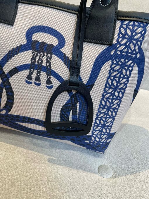HERMÈS Steeple 25 Bag. Authentic quality luxury bag crafted in genuine leather comes with authenticity card, dust bag and gift bag. Where art meets heritage. The Hermès Steeple Bag is a charming fusion of heritage and artistry, crafted from a blend of canvas and Swift leather. Its design pays tribute to Hermès’ equestrian roots with whip-shaped handles and a stirrup-inspired charm, adding a playful yet sophisticated touch. Lightweight yet spacious, the Steeple is ideal for daily use. Whether you opt for a vibrant motif or a sleek, single-color design, this bag stands out as an artistic expression of luxury that seamlessly integrates into a modern lifestyle. Praised for its unique aesthetic and accessibility within the Hermès lineup, the Steeple Bag is adored by fashion enthusiasts who appreciate its colorful palette and bold personality. While it’s best suited for those who enjoy the texture and look of canvas, it remains a versatile statement piece that captures the spirit of everyday elegance.
