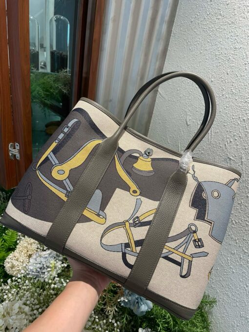 HERMÈS Garden Party Voyage. Authentic quality luxury bag crafted in genuine leather comes with authenticity card, dust bag and gift bag. The Art of Everyday Escape. Chic, structured, and effortlessly refined, the HERMÈS Garden Party Voyage is the perfect companion for your daily adventures or spontaneous weekend getaways. Crafted with precision in supple Negonda leather or canvas with leather trim, this midsize tote strikes the perfect balance between luxury and functionality. Its minimalist silhouette is elevated by discreet Clou de Selle snap closures and expandable sides, offering both form and flexibility. Spacious enough for your essentials yet compact enough to carry with ease, it’s a timeless piece designed to move with you—gracefully. Whether carried in hand or worn over the shoulder, the Garden Party Voyage 36 speaks in whispers of elegance and unmistakable HERMÈS craftsmanship. Every day is a journey. Travel beautifully.