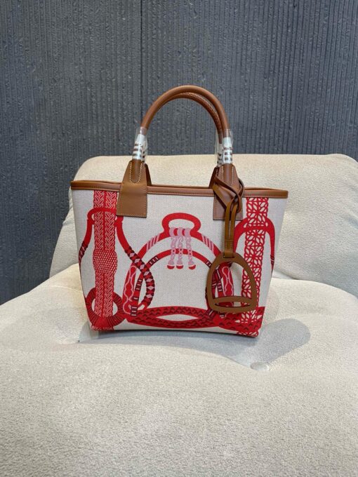 HERMÈS Steeple 25 Bag. Authentic quality luxury bag crafted in genuine leather comes with authenticity card, dust bag and gift bag. Where art meets heritage. The Hermès Steeple Bag is a charming fusion of heritage and artistry, crafted from a blend of canvas and Swift leather. Its design pays tribute to Hermès’ equestrian roots with whip-shaped handles and a stirrup-inspired charm, adding a playful yet sophisticated touch. Lightweight yet spacious, the Steeple is ideal for daily use. Whether you opt for a vibrant motif or a sleek, single-color design, this bag stands out as an artistic expression of luxury that seamlessly integrates into a modern lifestyle. Praised for its unique aesthetic and accessibility within the Hermès lineup, the Steeple Bag is adored by fashion enthusiasts who appreciate its colorful palette and bold personality. While it’s best suited for those who enjoy the texture and look of canvas, it remains a versatile statement piece that captures the spirit of everyday elegance.
