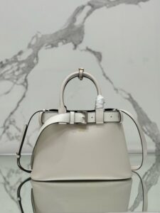 PRADA Buckle Small Leather Handbag. Authentic quality luxury bag crafted in genuine leather comes with authenticity card, dust bag and gift bag. Sophistication Meets Utility. Sleek, structured, and undeniably Prada — the Buckle Small Leather Handbag captures the brand’s signature balance of minimalist elegance and refined detail. Crafted in smooth leather with a buttery-soft nappa interior, this compact piece is a masterclass in functional luxury. A standout feature? Its interchangeable belt strap, adding a bold, modern twist to the timeless silhouette. Whether you're heading to a meeting or a soirée, this bag adapts seamlessly to your mood and moment. Finished with the embossed iconic PRADA logo, it’s a quiet statement of taste and distinction. A versatile companion for the woman who appreciates precision, polish, and just the right touch of edge. - KRIS + KIKO PRADA Buckle Small Leather Handbag. Authentic quality luxury bag crafted in genuine leather comes with authenticity card, dust bag and gift bag. Sophistication Meets Utility. Sleek, structured, and undeniably Prada — the Buckle Small Leather Handbag captures the brand’s signature balance of minimalist elegance and refined detail. Crafted in smooth leather with a buttery-soft nappa interior, this compact piece is a masterclass in functional luxury. A standout feature? Its interchangeable belt strap, adding a bold, modern twist to the timeless silhouette. Whether you're heading to a meeting or a soirée, this bag adapts seamlessly to your mood and moment. Finished with the embossed iconic PRADA logo, it’s a quiet statement of taste and distinction. A versatile companion for the woman who appreciates precision, polish, and just the right touch of edge.