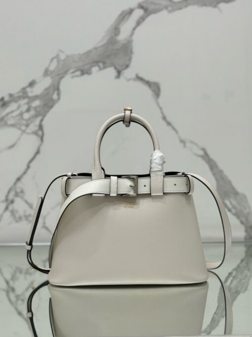 PRADA Buckle Small Leather Handbag. Authentic quality luxury bag crafted in genuine leather comes with authenticity card, dust bag and gift bag. Sophistication Meets Utility. Sleek, structured, and undeniably Prada — the Buckle Small Leather Handbag captures the brand’s signature balance of minimalist elegance and refined detail. Crafted in smooth leather with a buttery-soft nappa interior, this compact piece is a masterclass in functional luxury. A standout feature? Its interchangeable belt strap, adding a bold, modern twist to the timeless silhouette. Whether you're heading to a meeting or a soirée, this bag adapts seamlessly to your mood and moment. Finished with the embossed iconic PRADA logo, it’s a quiet statement of taste and distinction. A versatile companion for the woman who appreciates precision, polish, and just the right touch of edge.