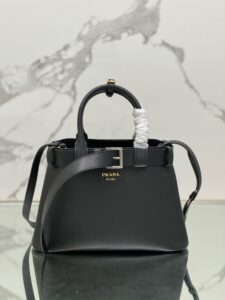 PRADA Buckle Small Leather Handbag. Authentic quality luxury bag crafted in genuine leather comes with authenticity card, dust bag and gift bag. Sophistication Meets Utility. Sleek, structured, and undeniably Prada — the Buckle Small Leather Handbag captures the brand’s signature balance of minimalist elegance and refined detail. Crafted in smooth leather with a buttery-soft nappa interior, this compact piece is a masterclass in functional luxury. A standout feature? Its interchangeable belt strap, adding a bold, modern twist to the timeless silhouette. Whether you're heading to a meeting or a soirée, this bag adapts seamlessly to your mood and moment. Finished with the embossed iconic PRADA logo, it’s a quiet statement of taste and distinction. A versatile companion for the woman who appreciates precision, polish, and just the right touch of edge.