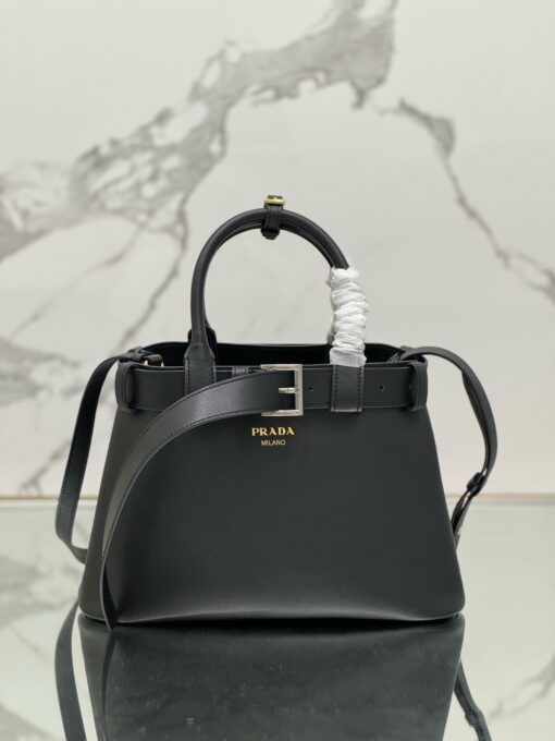 PRADA Buckle Small Leather Handbag. Authentic quality luxury bag crafted in genuine leather comes with authenticity card, dust bag and gift bag. Sophistication Meets Utility. Sleek, structured, and undeniably Prada — the Buckle Small Leather Handbag captures the brand’s signature balance of minimalist elegance and refined detail. Crafted in smooth leather with a buttery-soft nappa interior, this compact piece is a masterclass in functional luxury. A standout feature? Its interchangeable belt strap, adding a bold, modern twist to the timeless silhouette. Whether you're heading to a meeting or a soirée, this bag adapts seamlessly to your mood and moment. Finished with the embossed iconic PRADA logo, it’s a quiet statement of taste and distinction. A versatile companion for the woman who appreciates precision, polish, and just the right touch of edge.