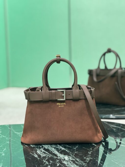 PRADA Buckle Small Leather Handbag. Authentic quality luxury bag crafted in genuine leather comes with authenticity card, dust bag and gift bag. Sophistication Meets Utility. Sleek, structured, and undeniably Prada — the Buckle Small Leather Handbag captures the brand’s signature balance of minimalist elegance and refined detail. Crafted in smooth leather with a buttery-soft nappa interior, this compact piece is a masterclass in functional luxury. A standout feature? Its interchangeable belt strap, adding a bold, modern twist to the timeless silhouette. Whether you're heading to a meeting or a soirée, this bag adapts seamlessly to your mood and moment. Finished with the embossed iconic PRADA logo, it’s a quiet statement of taste and distinction. A versatile companion for the woman who appreciates precision, polish, and just the right touch of edge.