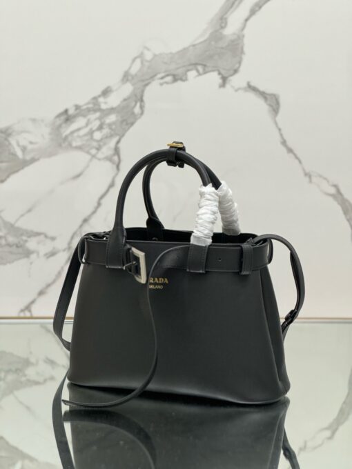 PRADA Buckle Small Leather Handbag. Authentic quality luxury bag crafted in genuine leather comes with authenticity card, dust bag and gift bag. Sophistication Meets Utility. Sleek, structured, and undeniably Prada — the Buckle Small Leather Handbag captures the brand’s signature balance of minimalist elegance and refined detail. Crafted in smooth leather with a buttery-soft nappa interior, this compact piece is a masterclass in functional luxury. A standout feature? Its interchangeable belt strap, adding a bold, modern twist to the timeless silhouette. Whether you're heading to a meeting or a soirée, this bag adapts seamlessly to your mood and moment. Finished with the embossed iconic PRADA logo, it’s a quiet statement of taste and distinction. A versatile companion for the woman who appreciates precision, polish, and just the right touch of edge.