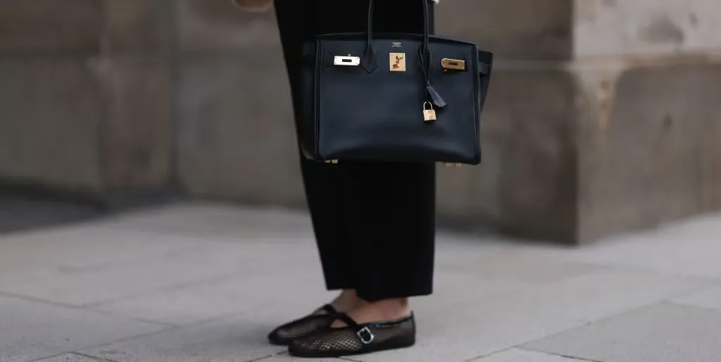 Fashion-forward man with a pastel replica BIRKIN at a rooftop party