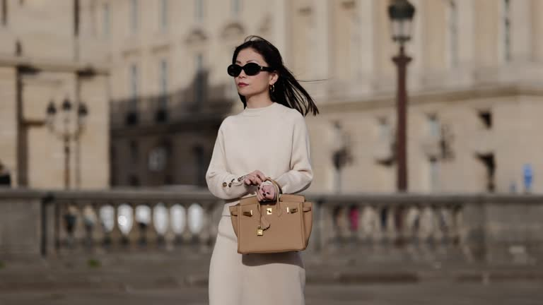 Woman in oversized sunglasses walking in SoHo with pastel Hermès-style bag Woman in oversized sunglasses walking in SoHo with pastel Hermès-style bag